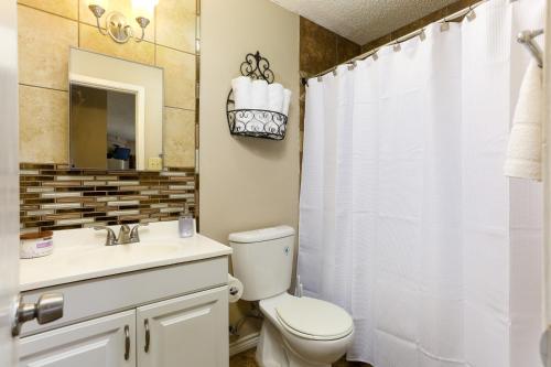a bathroom with a toilet and a sink and a mirror at Home with pool near Sea World & Lackland in San Antonio