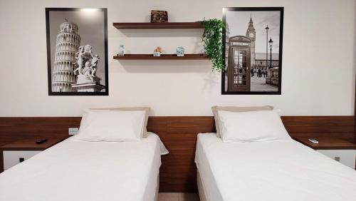 two beds in a room with two pictures on the wall at Lindos Studios Centro/Wifi/Garagem in Foz do Iguaçu