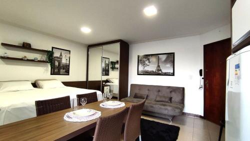 a bedroom with a bed and a table and a couch at Lindos Studios Centro/Wifi/Garagem in Foz do Iguaçu
