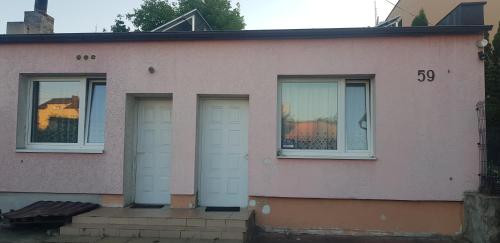 Una casa rosa con dos puertas blancas. en Noclegi, en Starogard Gdański
