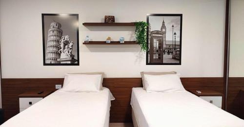 two beds in a room with two pictures on the wall at Lindos Studios Centro/Wifi/Garagem in Foz do Iguaçu