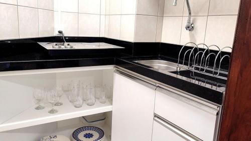 a white and black kitchen with a sink and glasses at Lindos Studios Centro/Wifi/Garagem in Foz do Iguaçu