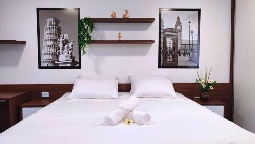 a bedroom with two beds with white sheets and pictures at Lindos Studios Centro/Wifi/Garagem in Foz do Iguaçu