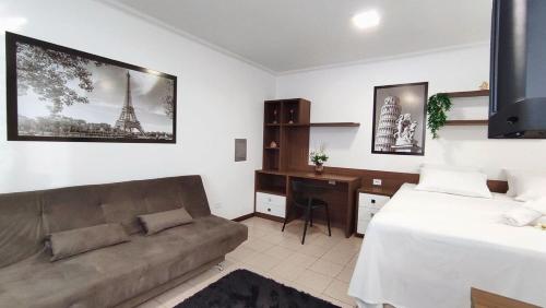 a bedroom with a couch and a bed and a desk at Lindos Studios Centro/Wifi/Garagem in Foz do Iguaçu