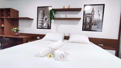 a bedroom with two beds with white sheets and towels at Lindos Studios Centro/Wifi/Garagem in Foz do Iguaçu