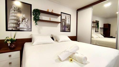 a bedroom with two beds with white sheets and a mirror at Lindos Studios Centro/Wifi/Garagem in Foz do Iguaçu
