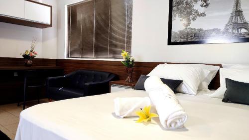 a bedroom with a white bed with flowers on it at Lindos Studios Centro/Wifi/Garagem in Foz do Iguaçu