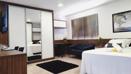 a room with a bed and a desk and a mirror at Lindos Studios Centro/Wifi/Garagem in Foz do Iguaçu