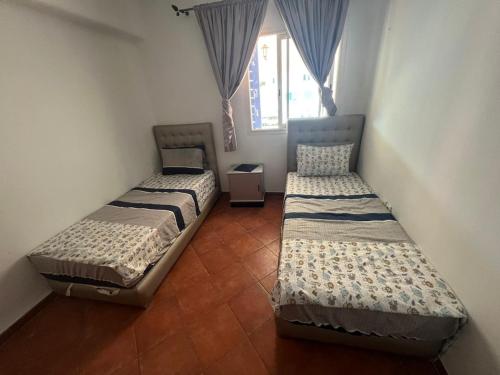 - 2 lits jumeaux dans une chambre avec fenêtre dans l'établissement Un bel appartement à Jawhara Smir, Marina Smir, à Marina Smir