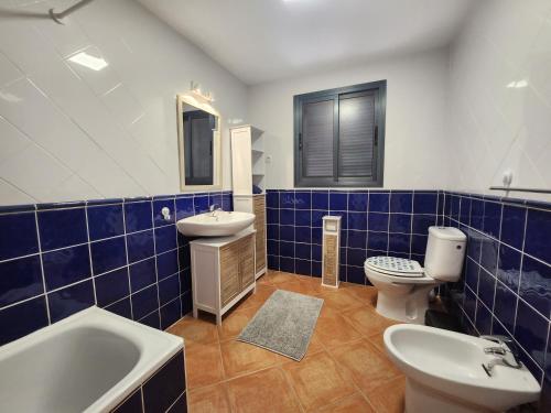 een blauw betegelde badkamer met een wastafel en een toilet bij BALCÓN DEL ATLANTICO CALETA de FUSTE in Caleta De Fuste