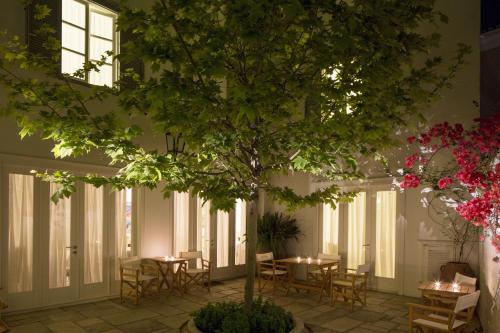 a courtyard with tables and a tree in a building at Hotel Leto Hydra in Hydra