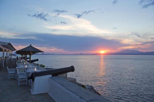 a sunset over the water with a table and chairs at Hotel Leto Hydra in Hydra
