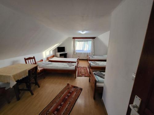 an attic room with three beds and a table and chairs at Betty Panzio in Miercurea-Ciuc
