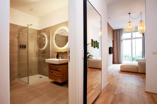 ein Bad mit einer Dusche, einem Waschbecken und einem Spiegel in der Unterkunft FERDI Margareten in Wien
