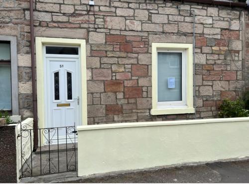 a brick building with a white door and windows at 51 Innes Street Apartment in Inverness