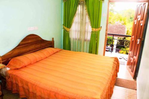 little rose inn في ويلاوايا: غرفة نوم بسرير ولحاف برتقالي