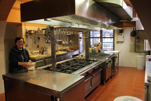 a woman standing in a kitchen with a stove at Villa Delia Hotel and Cooking School in Ripoli