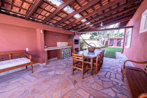 a patio with a table and chairs in a room at 4 dorm com piscina a 350 m de Camburizinho in Camburi