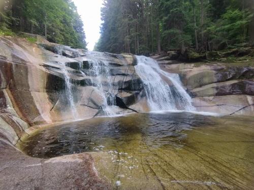 a waterfall on the rocks with a pool of water at Privat Pohoda in Paseky nad Jizerou
