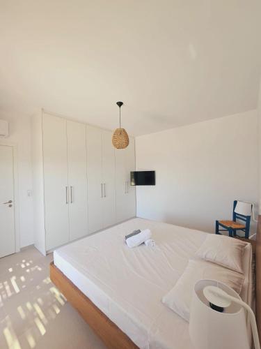 a white bedroom with a large white bed and a lamp at Villa Milan 1 mit Padelplatz in Kos Town