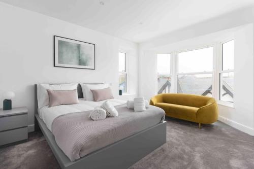 3 Bed, sea views, central Penzance,newly renovated في بينزانس: غرفة نوم بسرير وكرسي اصفر