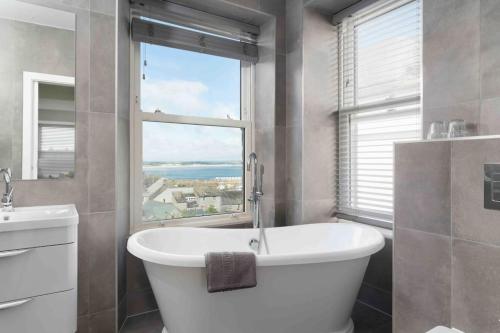 3 Bed, sea views, central Penzance,newly renovated في بينزانس: حمام مع حوض أبيض كبير ونافذة