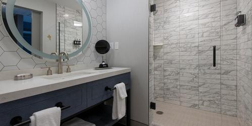 een badkamer met een wastafel, een spiegel en een douche bij Oak Grove Racing Gaming Hotel in Oak Grove