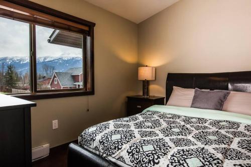 a bedroom with a bed and a window with mountains at The best 2 bedrooms suite in Revelstoke! in Revelstoke
