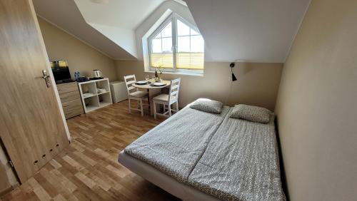 a bedroom with a bed and a table and a window at Kwatery Mielenko Patraj in Mielenko