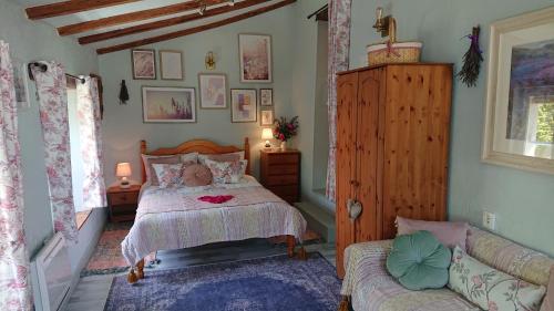 een slaapkamer met een bed en een bank bij La Colline de Tilleul - Les Deux Puits - Cosy Cottage with swimming pool near Aubeterre in Saint-Romain