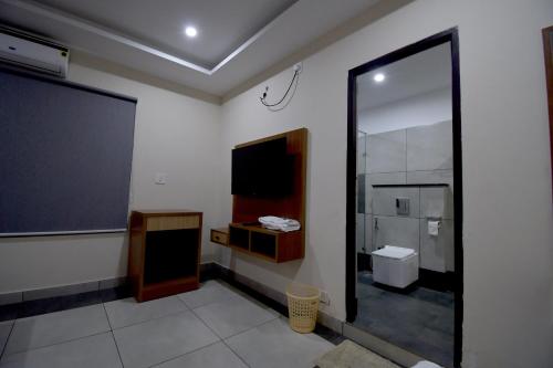 a bathroom with a large mirror and a tv at ARAKKAL GUESTHOUSE in Kalpetta