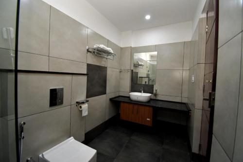 a bathroom with a sink and a toilet and a mirror at ARAKKAL GUESTHOUSE in Kalpetta