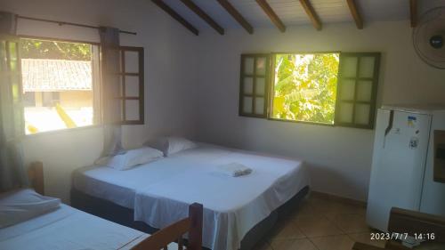 Pousada João e Maria في ترينيداد: سريرين في غرفة بها نافذتين