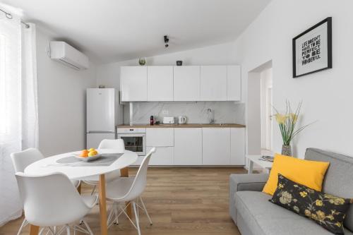 a kitchen and a living room with a table and chairs at Tonina apartment - house with patio, jacuzzi, free parking in Split
