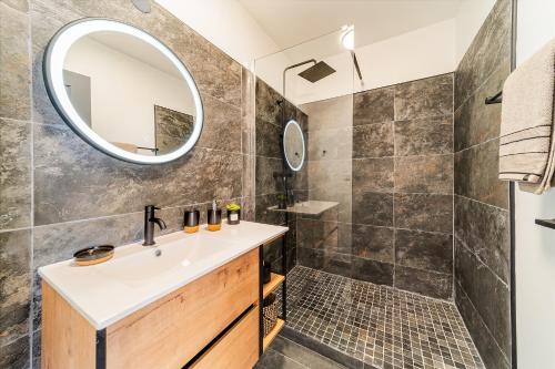 ein Bad mit einem Waschbecken und einer Dusche mit einem Spiegel in der Unterkunft Le point de vue Studio saint Denis in Saint-Denis