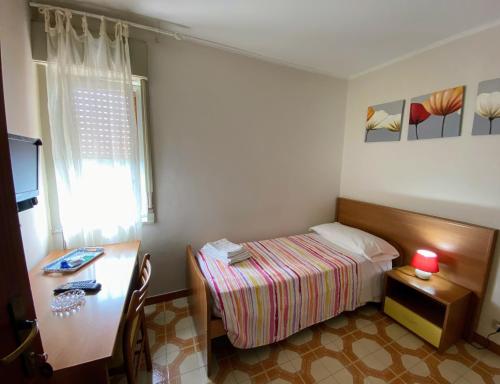 a small bedroom with a desk and a bed and a table at Albergo Mendolia in Milazzo