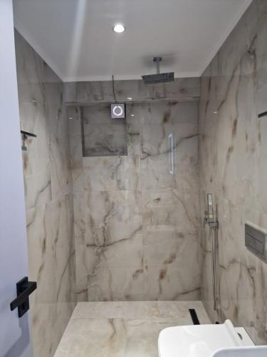 a bathroom with a marble shower and a sink at Sea's Villa in Ksamil