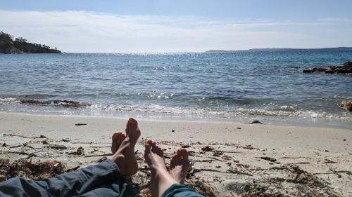 a person laying on the beach with their feet in the sand at Studio climatisé avec coin nuit 150m de la plage in Le Lavandou