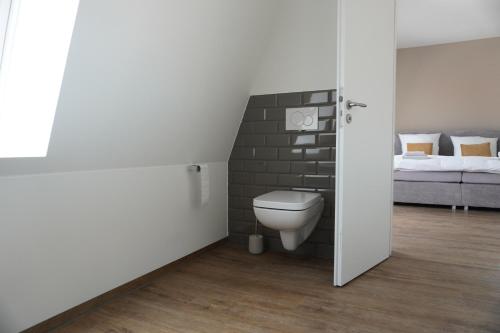a bathroom with a toilet in a brick wall at Sleepwell Apartment - Ehrensteinsuite in Leipzig