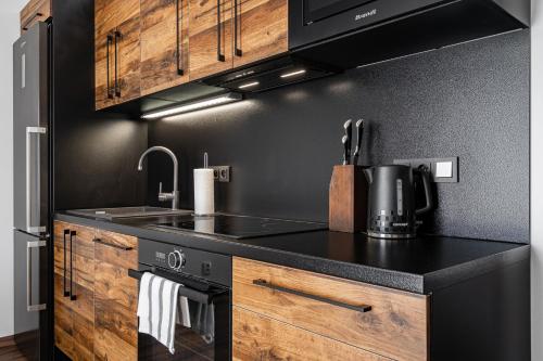 a kitchen with a black counter top and wooden cabinets at J-H APARTMÁNY HORSKÝ RESORT BUKOVÁ HORA - 100 m od LANOVKY in Červená Voda