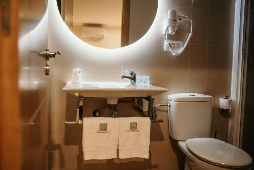 uma casa de banho com um lavatório, um WC e um espelho. em PENSIÓN BERENGUELA em Melide