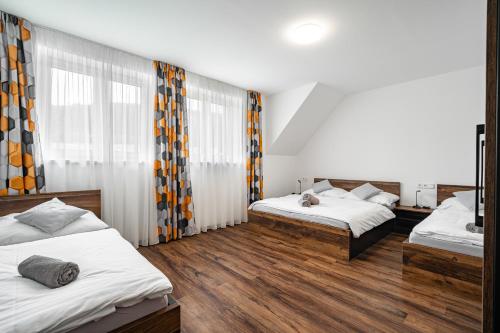 een slaapkamer met 2 bedden en gordijnen en houten vloeren bij J-H APARTMÁNY HORSKÝ RESORT BUKOVÁ HORA - 100 m od LANOVKY in Červená Voda