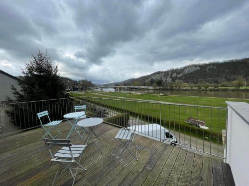 una terraza con sillas y mesas y vistas al río en Le Pré sous l'eau - NATURA, en Anhée