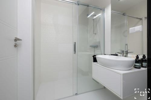 a white bathroom with a sink and a shower at Wave Międzyzdroje - Luxury 2 Bedroom Suite with Salon and Kitchen in Międzyzdroje