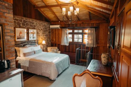 a bedroom with a bed and a brick wall at Villa Tuiuty Pousada de Charme in Bento Gonçalves