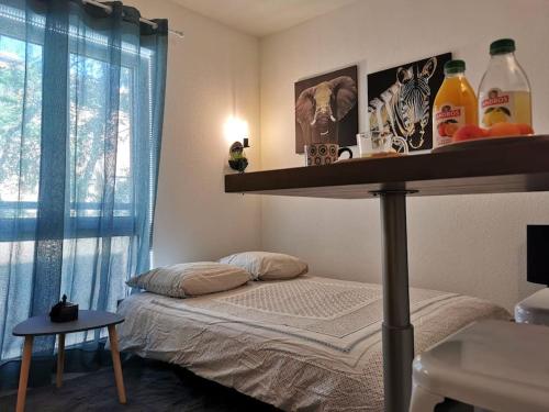 - une chambre avec un lit et une étagère avec des boissons dans l'établissement * Le STUDI, Studio Cosy, MBS, Wifi, Parking, Clim*, à Montpellier