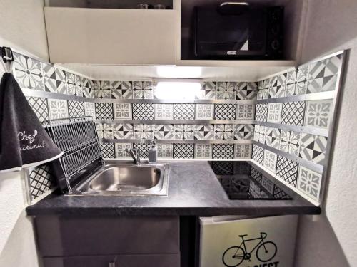 une petite cuisine avec un évier et un micro-ondes dans l'établissement * Le STUDI, Studio Cosy, MBS, Wifi, Parking, Clim*, à Montpellier