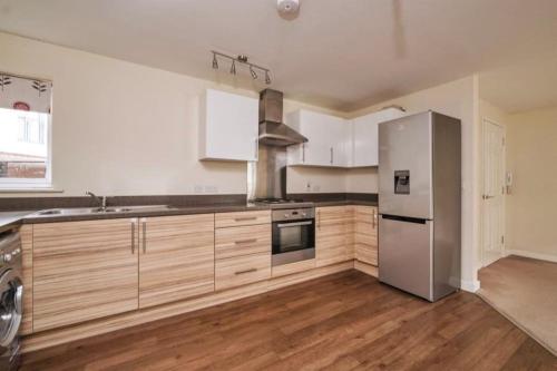 a kitchen with a stainless steel refrigerator and wooden cabinets at Sianavi Apartments in Kettering