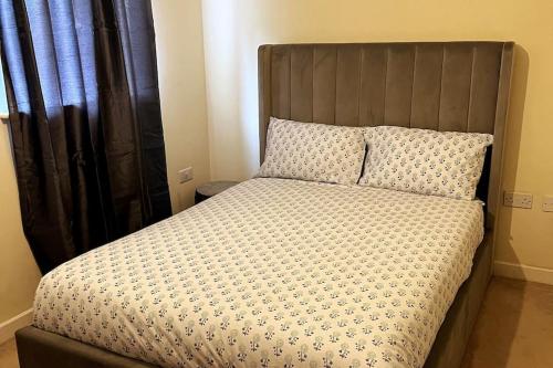 a bed with a wooden headboard in a bedroom at Sianavi Apartments in Kettering