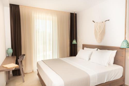 a bedroom with a large white bed and a window at CeraMio Suites in Limenas